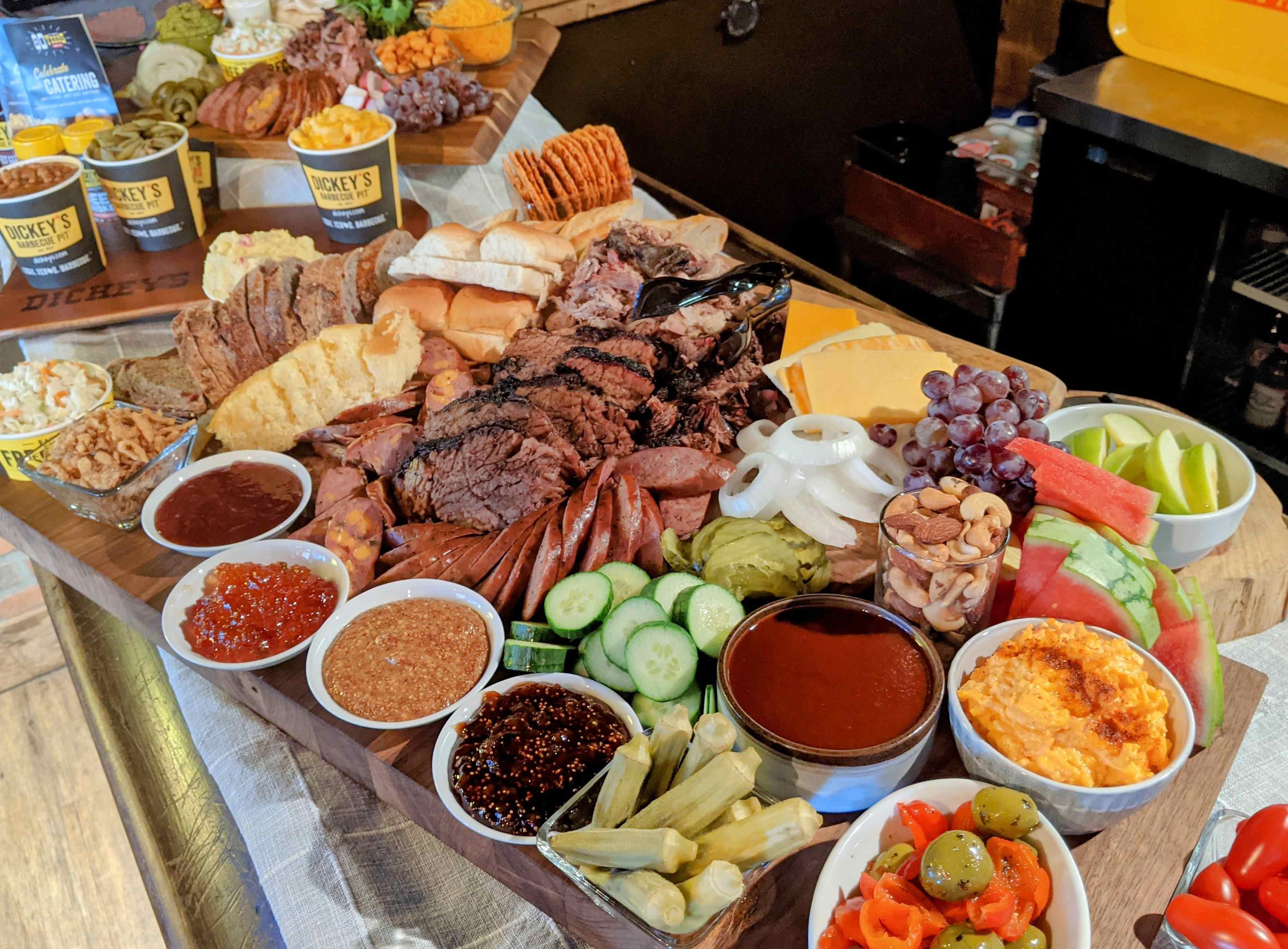 A large buffet spread with various BBQ meats, cheeses, fruits, vegetables, and different sauces.